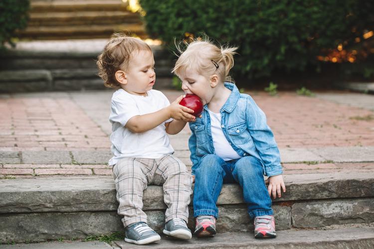 Photo of two children sharing an apple.